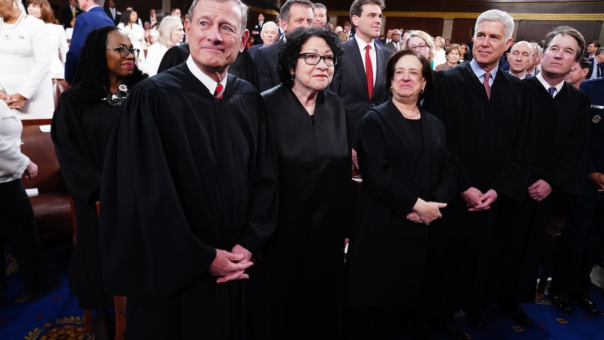 U.S. Supreme Court Justices, including Chief Justice John Roberts and Associate Justices Sonia Sotomayor, Elena Kagan, Neil Gorsuch, and Brett Kavanaugh, stand together on the House floor ahead of President Biden’s 2024 State of the Union address, surrounded by members of Congress and other attendees.