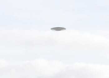 Flying saucer UFO over summer cloudy background sky, CGI recreation.