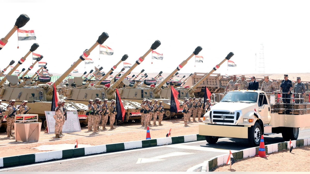 Egyptian President Abdel Fattah al-Sisi stands on a moving inspection vehicle alongside military officers as rows of Egyptian soldiers and self-propelled artillery units are displayed in Suez.