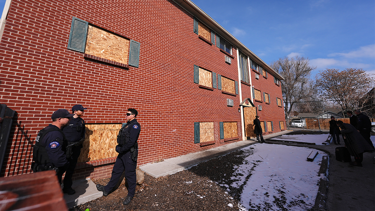 Officers gather outside one of the condemned buildings of an apartment complex called The Edge at Lowry