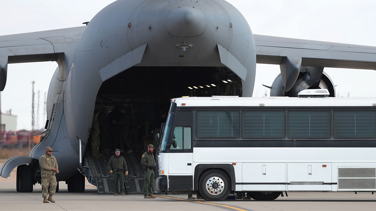 C-17 deportation plane next to a bus carrying migrants