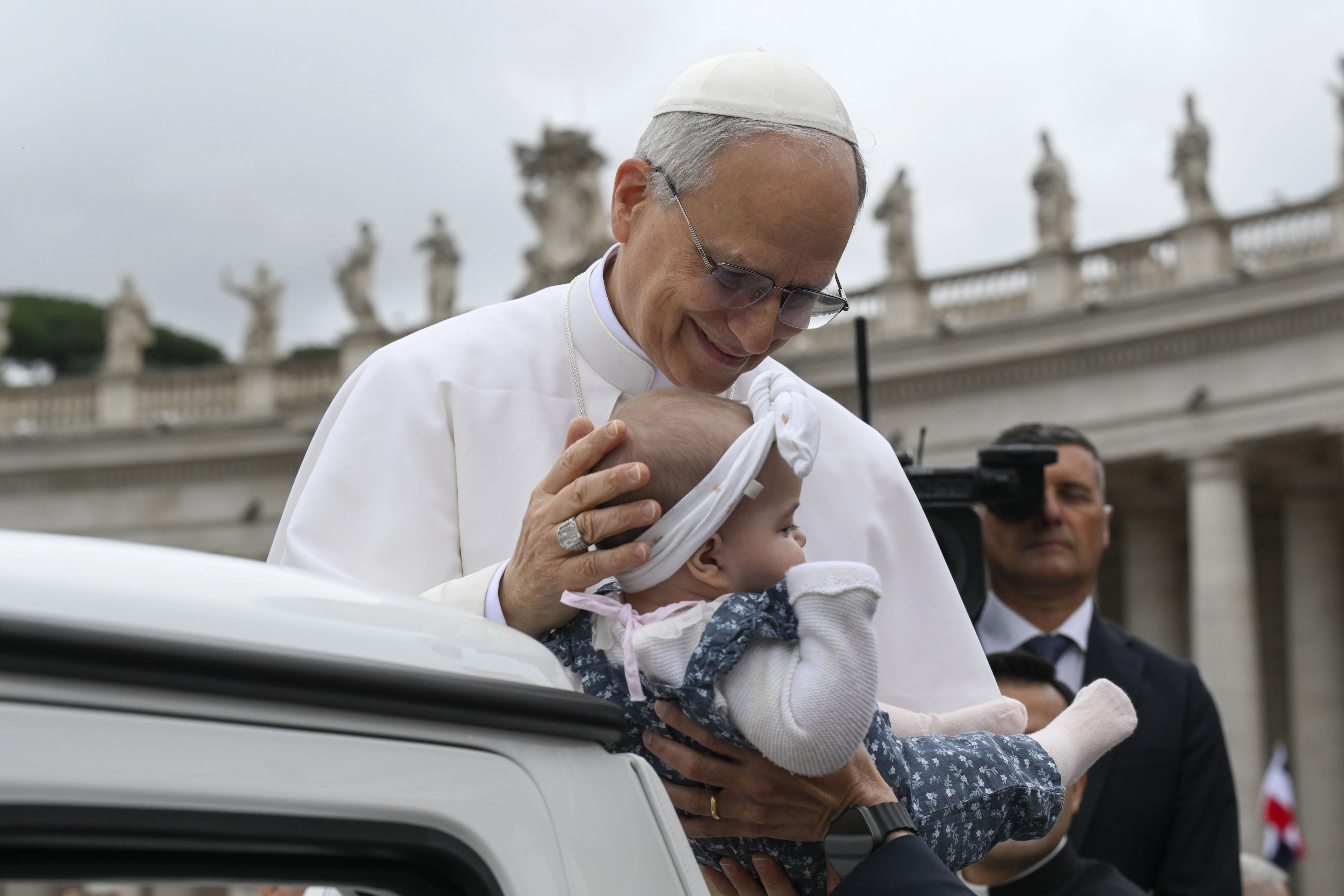Pope Leo XIV pauses to bless a baby during his trip around St. Peter's Square in the popemobile before the start of his first general audience on May 21, 2025. Credit: Vatican Media