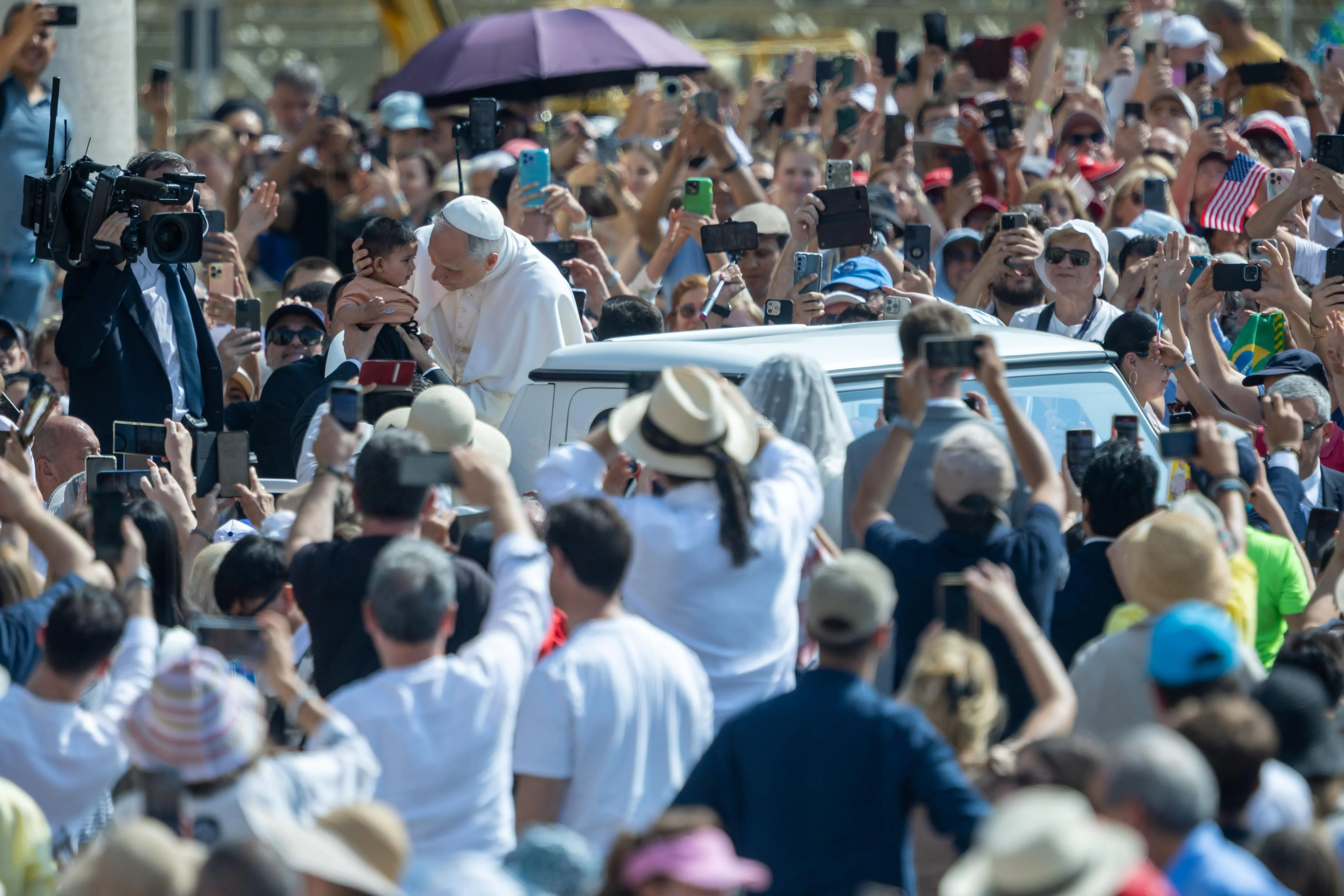 Pope Leo XIV embraces a baby during a ride around St. Peter's Square in the popemobile before the general audience on June 11, 2025. Credit: Daniel Ibanez/CNA