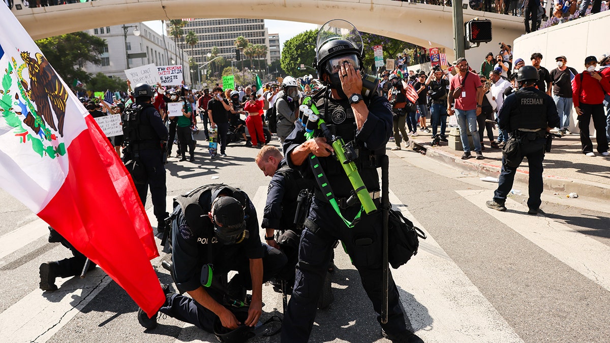 cops arresting protester at riot, Mexican flag at left in frame