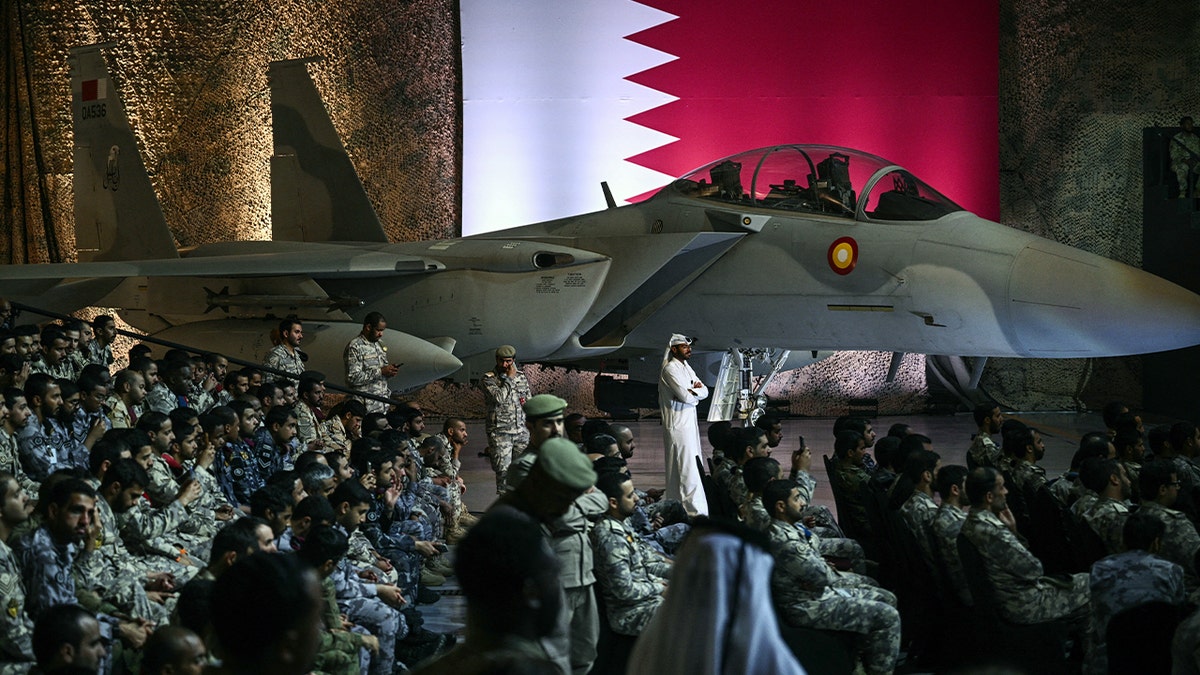 troops wait for Trump by jet in hangar, May 2025
