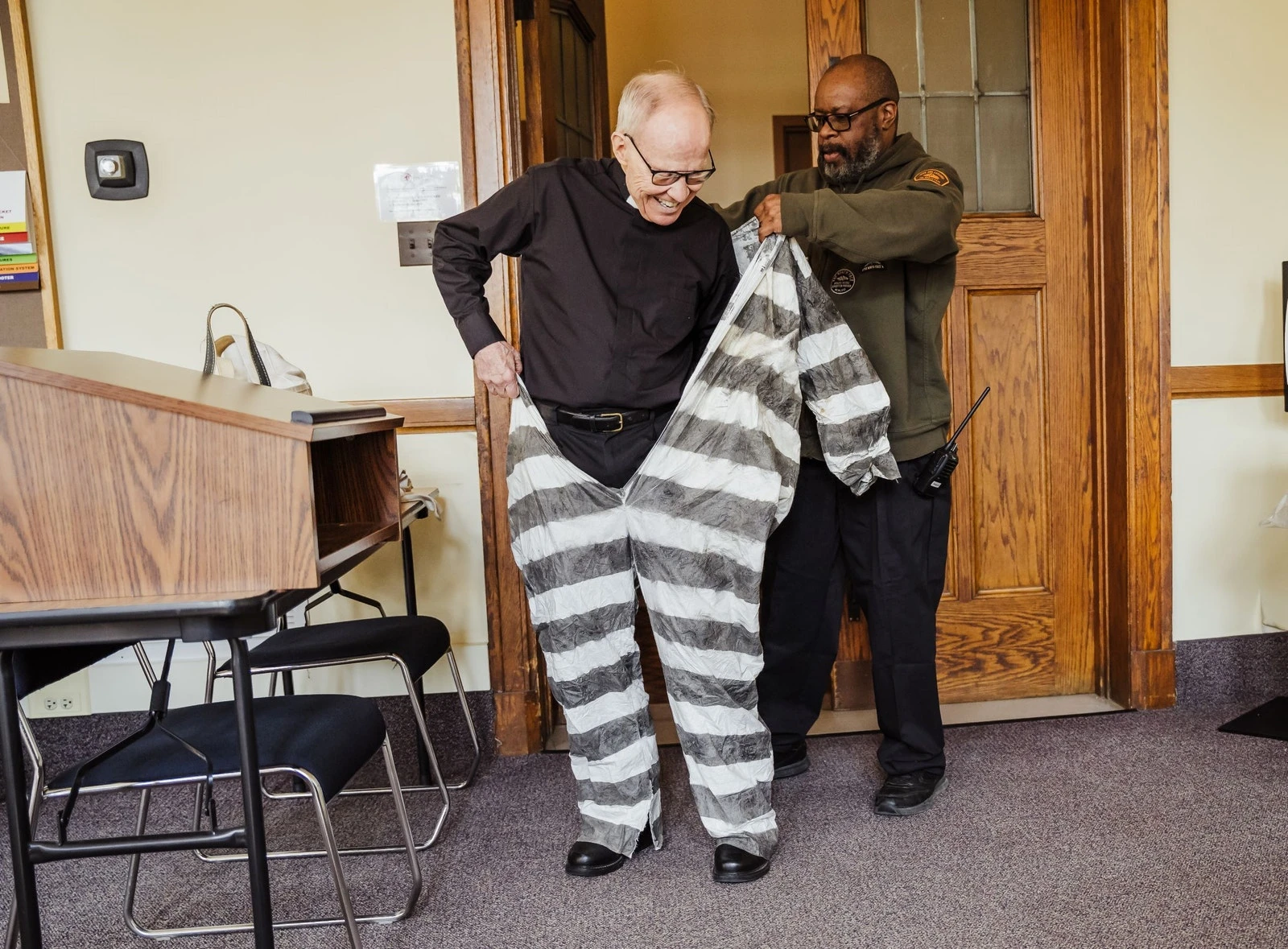 A security guard at Sacred Heart Major Seminary helps Fr. Cassidy don his "prisoner's clothing" for a photo shoot promoting Fr. Cassidy's latest book, "A Roman Commentary on St. Paul’s Letter to the Philippians," which details Paul's experience behind bars and the conditions under which he wrote his Letter to the Philippians. Valaurian Waller | Detroit Catholic