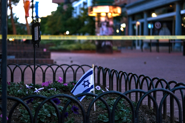 An Israeli flag stands in a bed of flowers as caution tape blocks off a deserted Pearl Street on the scene of an attack on demonstrators calling for the release of Israeli hostages held in Gaza, in Boulder, Colorado