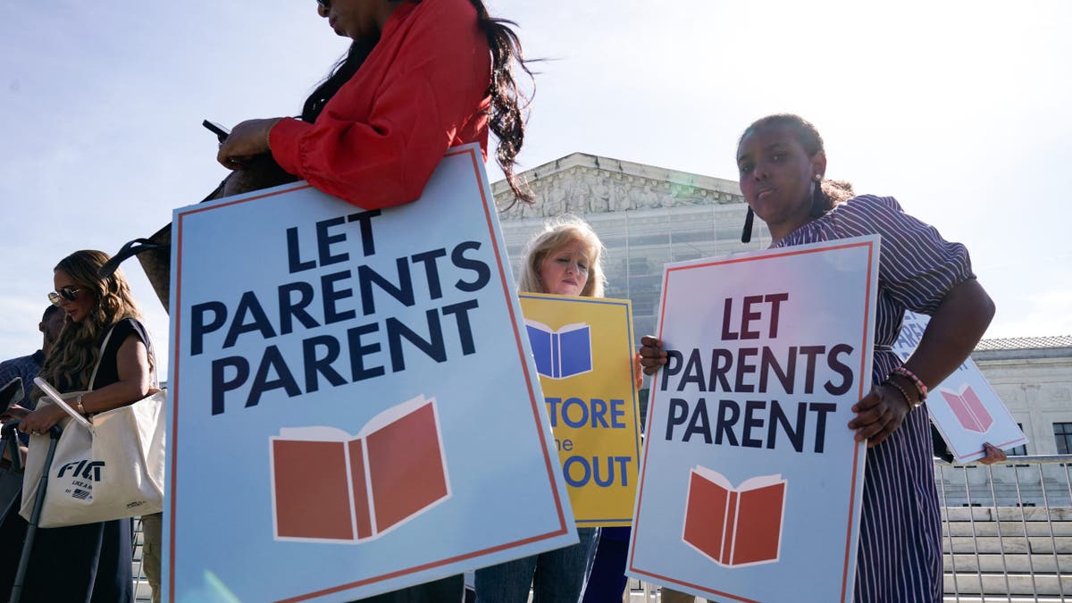 Parents and activists hold signs reading