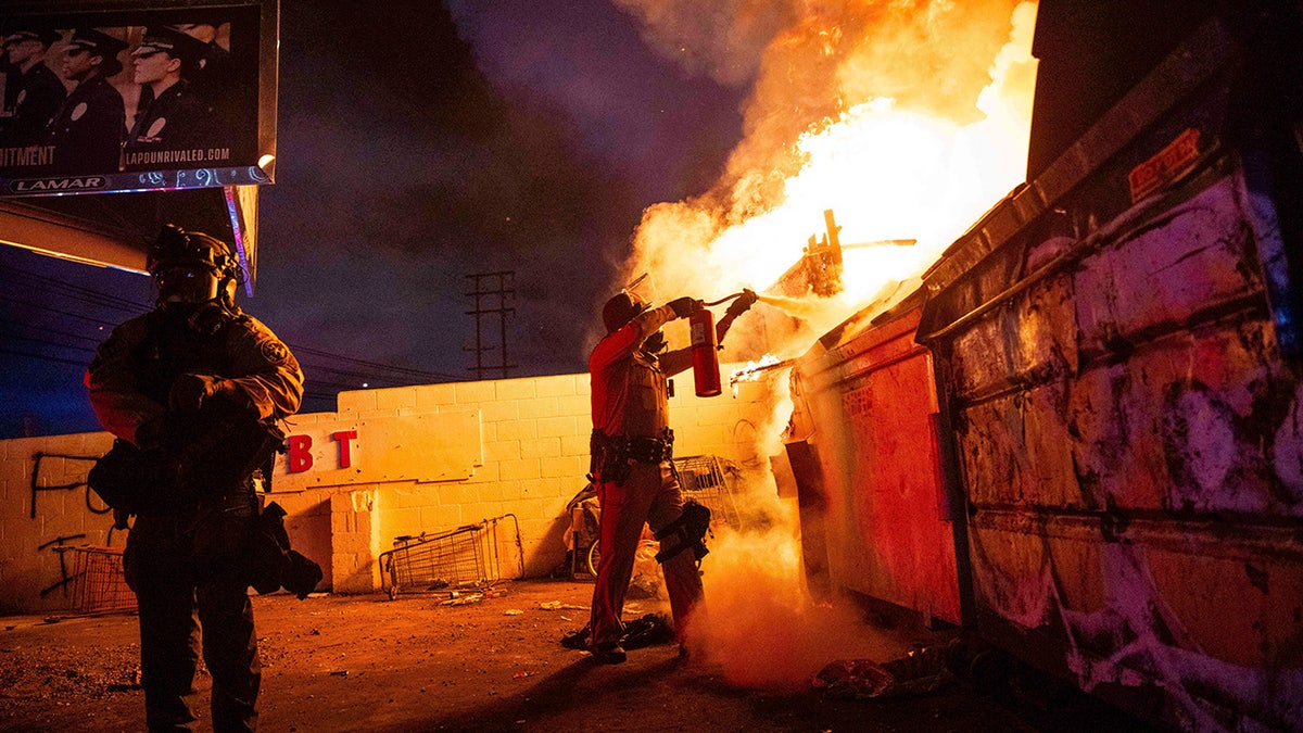 man aims fire extinguisher at blaze in LA riot