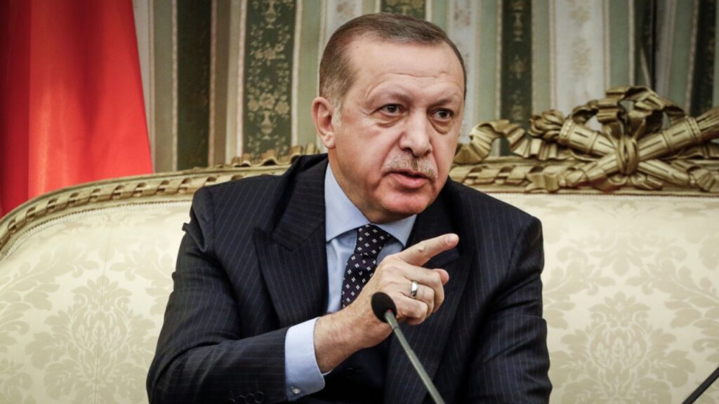 Turkish President Erdogan lectures reporters on a couch.