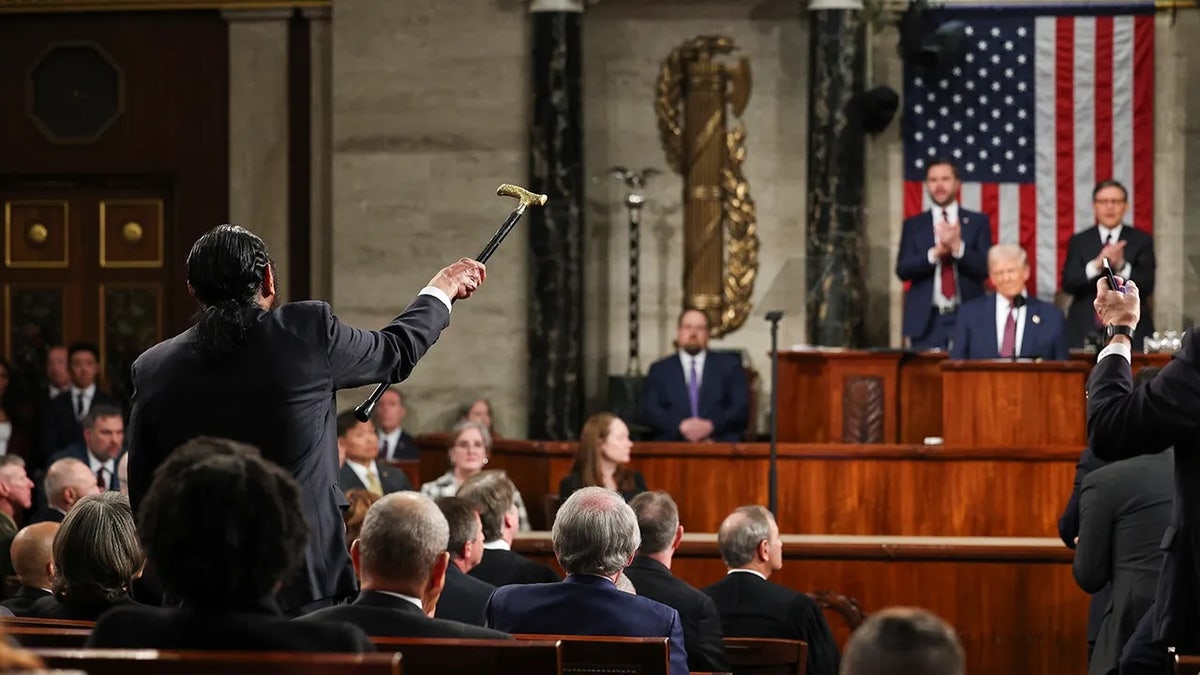 Green with cane raised, heckling Trump