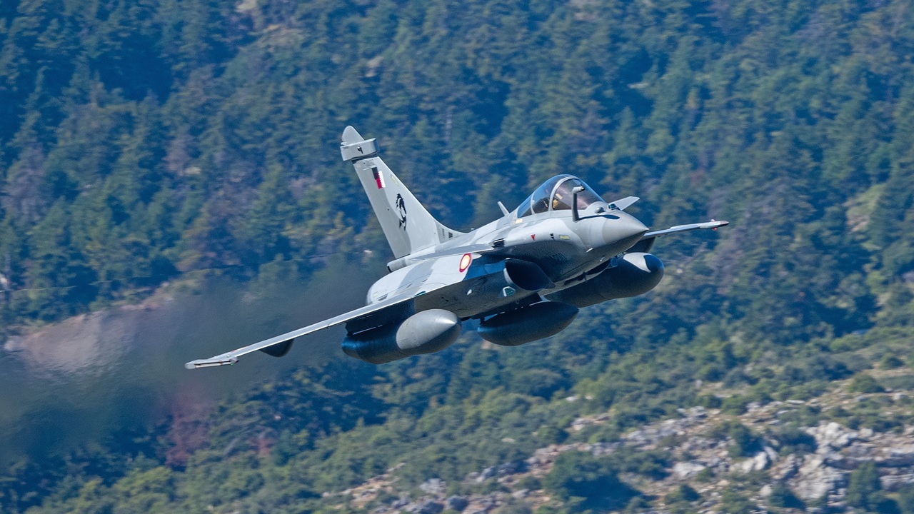 A Dassault Rafale fighter jet flying over woods.