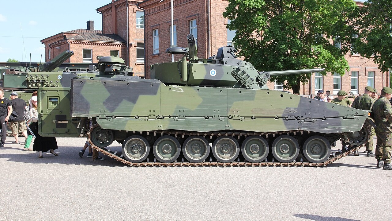CV90 on display next to soldiers.