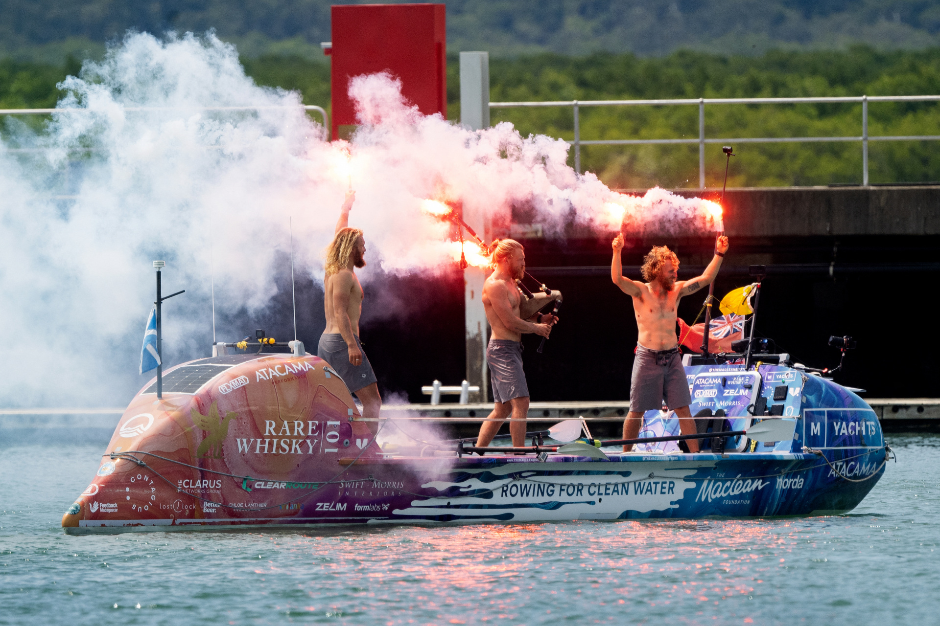 Three Scottish brothers (L-R) Lachlan, Jamie and Ewan MacLean celebrate as they arrive on their boat into Cairns in northern Queensland on August 30, 2025. The three Scottish brothers stepped ashore in Australia on August 30 after claiming a new record for rowing non-stop and unsupported across the Pacific Ocean, "over the moon" to be back on dry land. They set off in a carbon fibre dinghy from Lima in Peru in April for the 9,000 miles (14,500 kilometres) journey, enduring violent storms and sickness during their 139 days at sea. (Photo by Brian CASSEY / AFP) (Photo by BRIAN CASSEY/AFP via Getty Images)