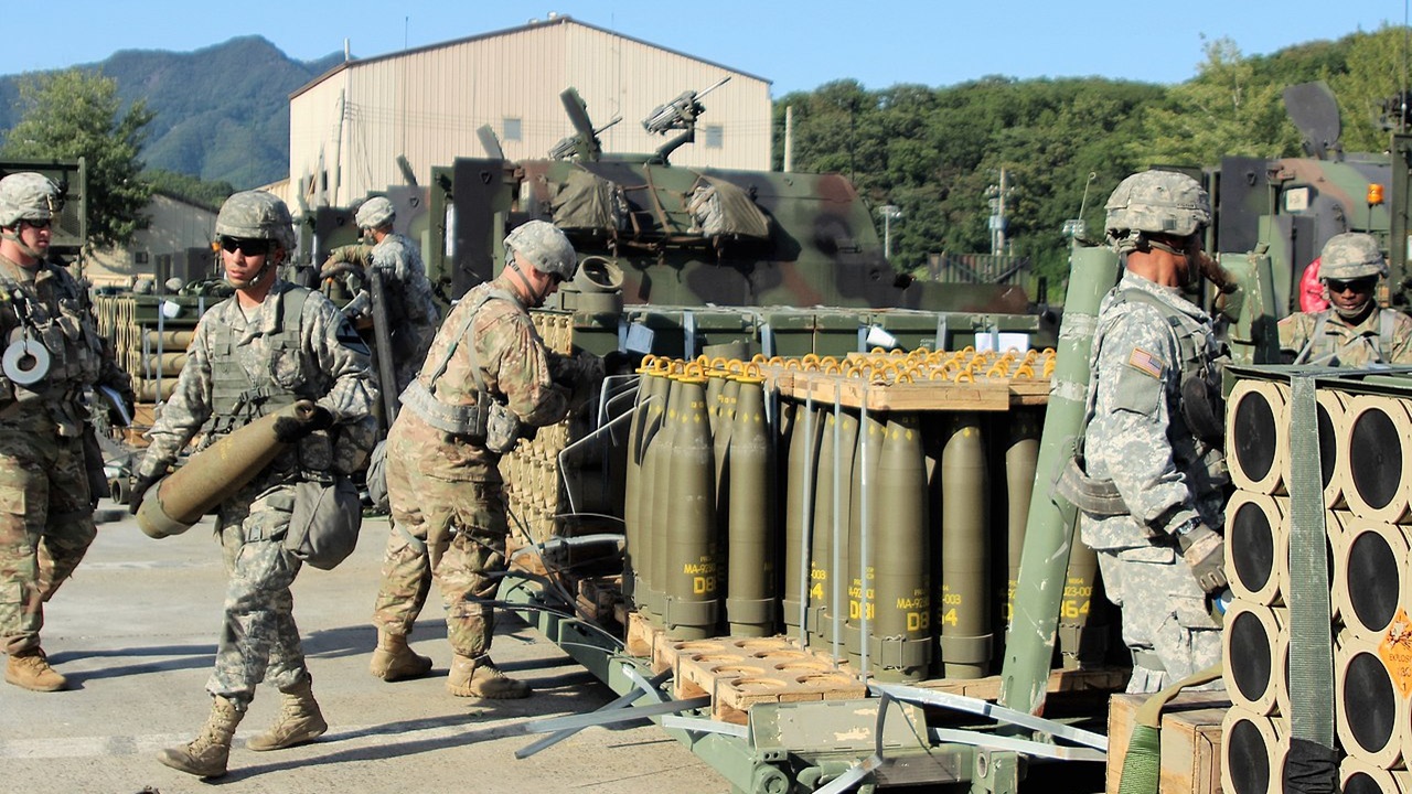 A group of soldiers near artillery ammunition.