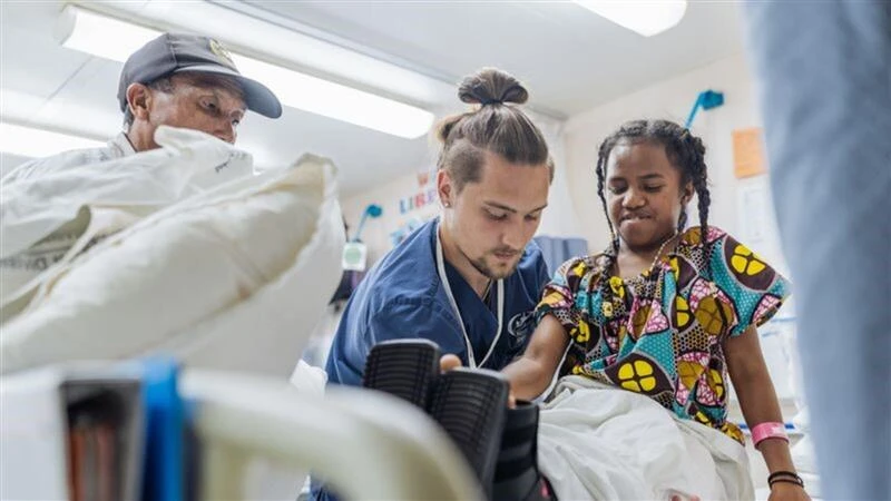 Erik Dike, a rising senior nursing student at Belmont Abbey College, with a patient at the ward onboard a hospital ship in Madagascar during a two-week program with Mercy Ships. Credit: Joshua Kiew Wing Chau