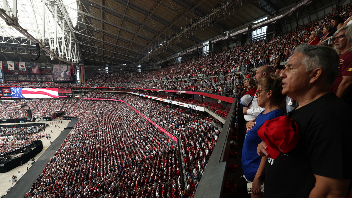 People stand as they attend the public memorial service for Charlie Kirk at State Farm Stadium in Glendale, Arizona, Sept. 21, 2025.