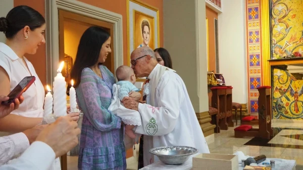 Father José Giner baptizes a baby. Credit: Father José Giner