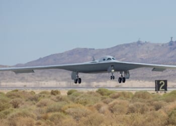 A B-21 Raider landing at an airfield.