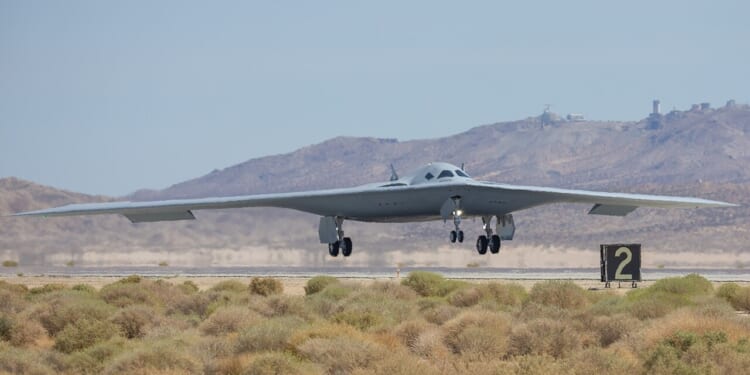 A B-21 Raider landing at an airfield.