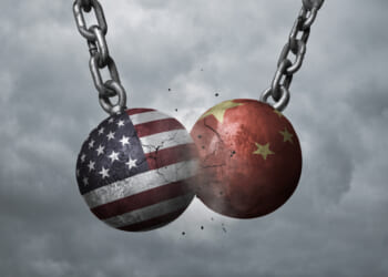 Two wrecking balls with american and chinese flags hitting each other, battery production weaponization concept
