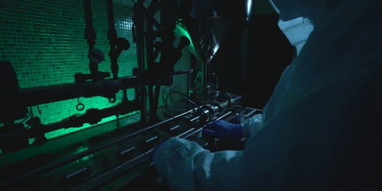 A woman in a face mask standing in front of scientific equipment.