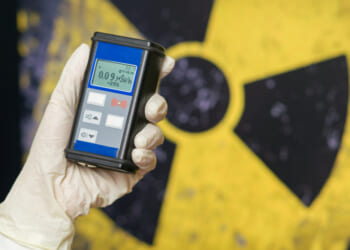 Radiation supervisor in glove with geiger counter checks the level of radiation in the radioactive zone