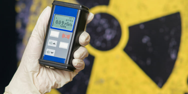 Radiation supervisor in glove with geiger counter checks the level of radiation in the radioactive zone