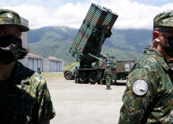Two Taiwanese soldiers in front of a missile launcher.