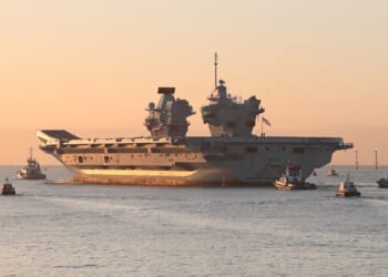 The HMS Prince of Wales sailing at sunset.