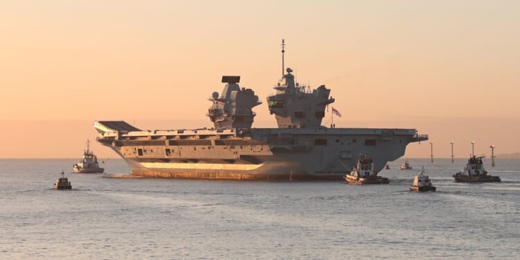 The HMS Prince of Wales sailing at sunset.