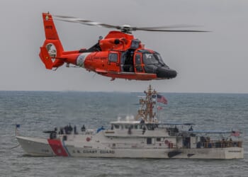 A Coast Guard ship and helicopter seen together.