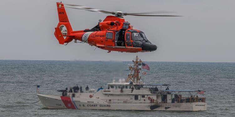 A Coast Guard ship and helicopter seen together.