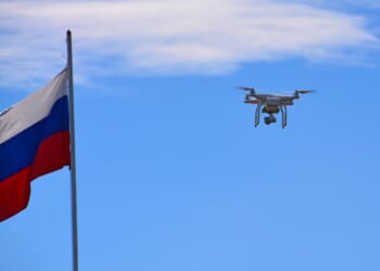 A drone flying next to a Russian flag.