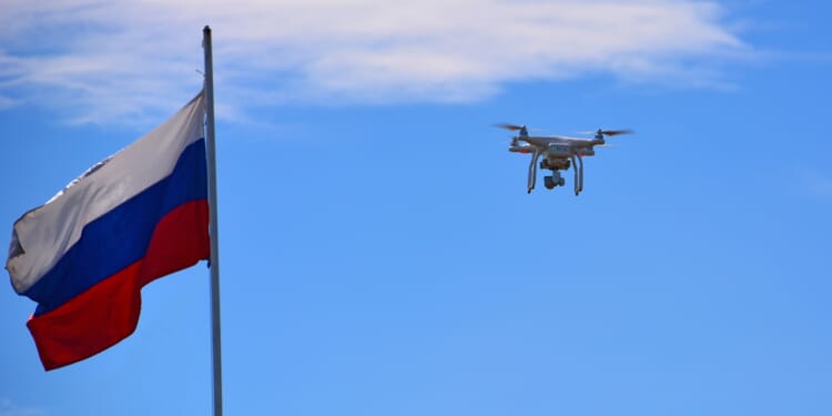 A drone flying next to a Russian flag.