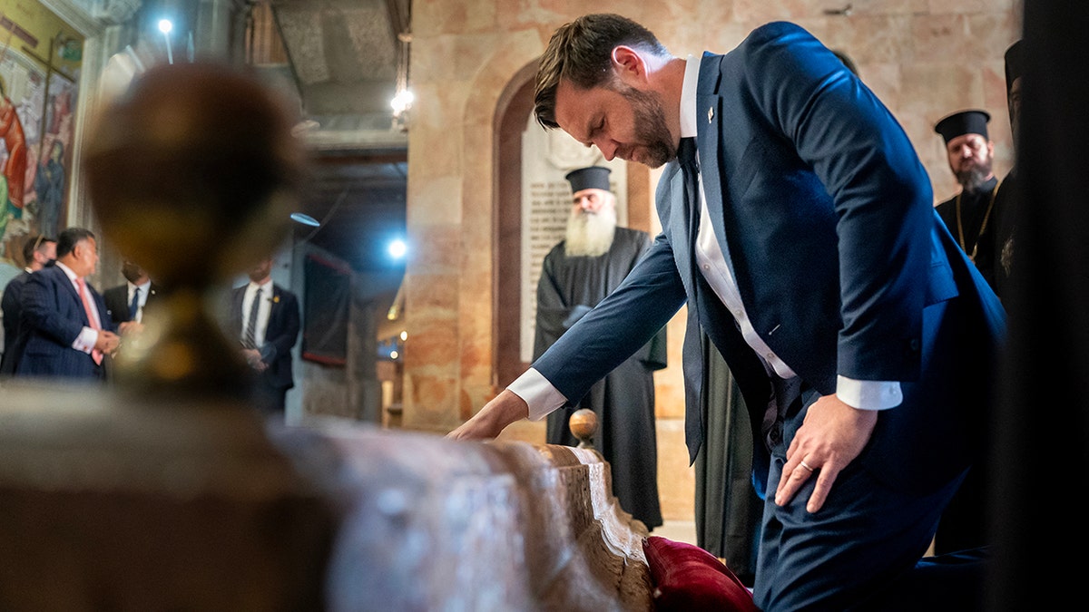 Vice President JD Vance places his hand on object as he tours The Church of the Holy Sepulchre