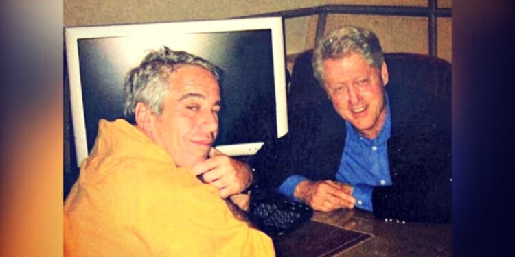 Two men posing together at a desk with a computer in the background, one wearing an orange hoodie and the other in a black jacket and blue shirt.