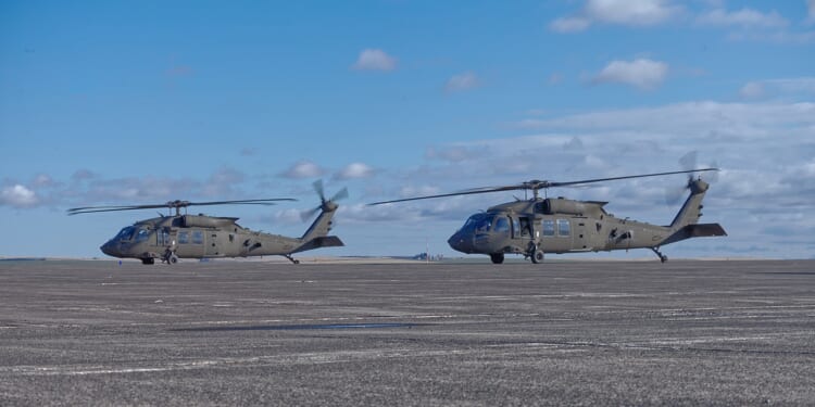Two Black Hawk helicopters at an airport.