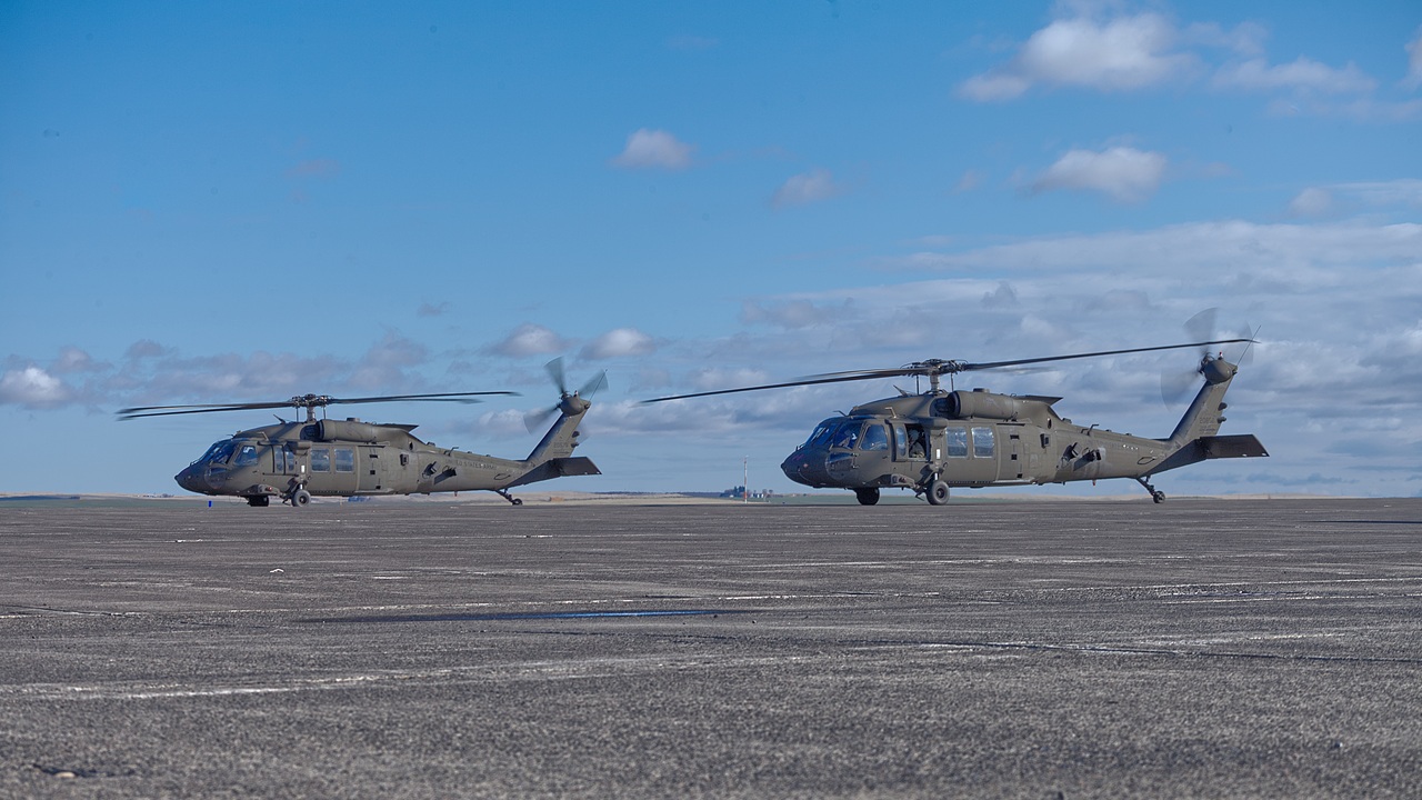 Two Black Hawk helicopters at an airport.