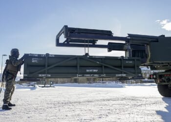 A soldier standing in front of a HIMARS vehicle.