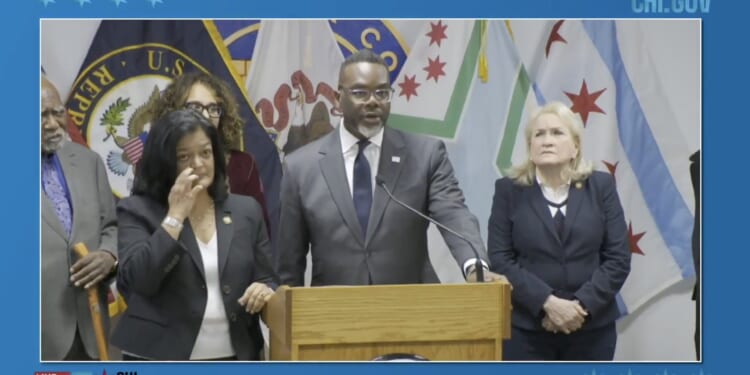 Press conference featuring Chicago officials discussing community initiatives, with multiple flags in the background and speakers at a podium.