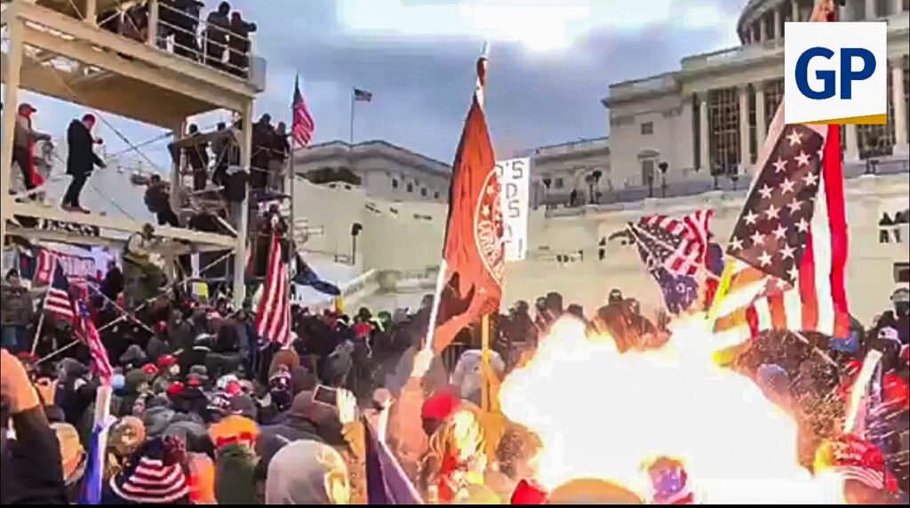 Crowd of protesters at the U.S. Capitol during a rally, waving flags and gathering near a fire, highlighting a significant moment in recent political history.