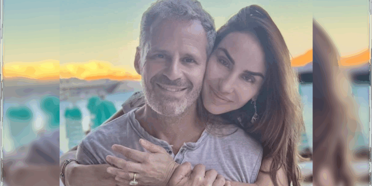 Couple smiling together outdoors with a scenic sunset background, showcasing affection and happiness in a relaxed setting.