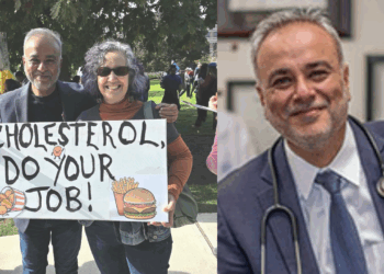 Two people hold a sign reading "Cholesterol, Do Your Job!" at a health awareness event, emphasizing the importance of managing cholesterol levels.