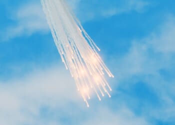 A group of white phosphorus flares falling from the sky.