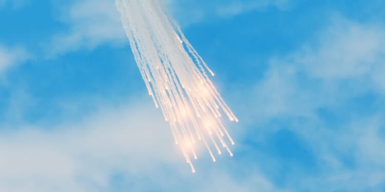 A group of white phosphorus flares falling from the sky.