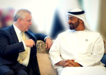 Two men engaged in a conversation on a sofa, representing diplomatic relations, with one in formal attire and the other in traditional Emirati dress.