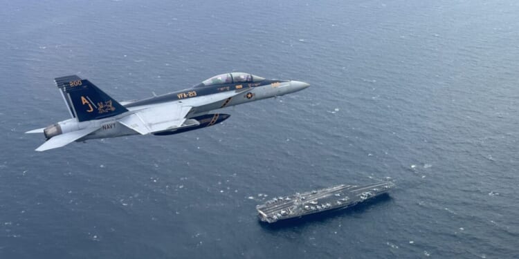 An F/A-18F Super Hornet, attached to Strike Fighter Squadron 213, piloted by Lt. Cmdr. Chris Kapuschansky with Gen. Sir Gwyn Jenkins, First Sea Lord and Chief of the Naval Staff, Royal Navy, embarked, flies over the world's largest aircraft carrier, USS Gerald R. Ford (CVN 78), in the North Sea, Sept. 26, 2025.