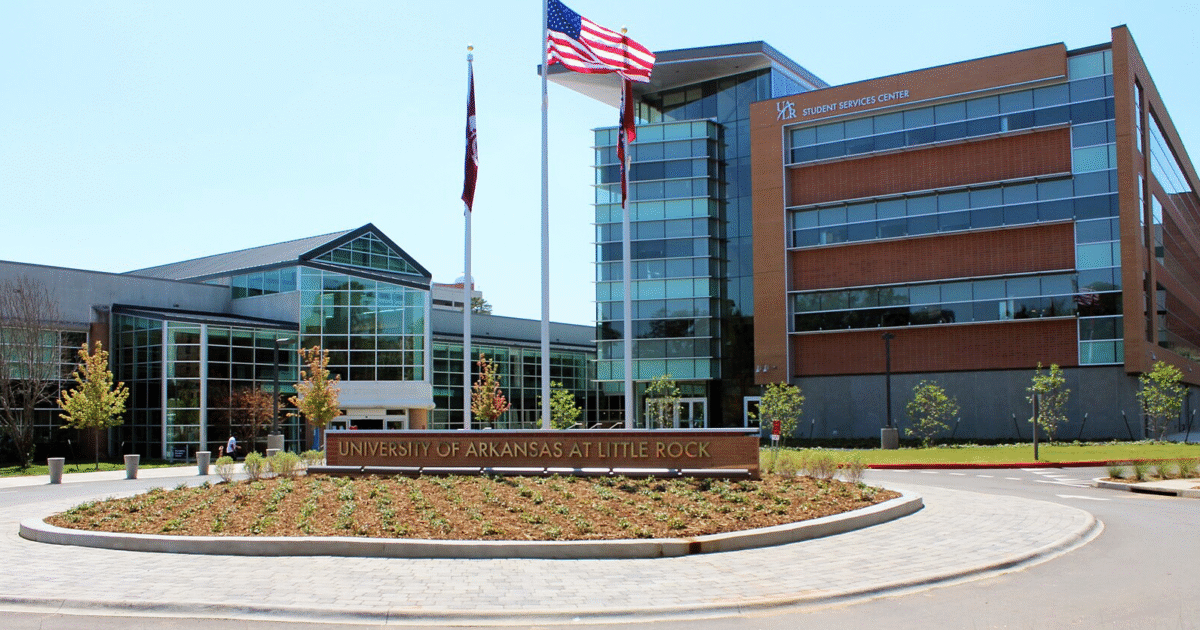 University of Arkansas at Little Rock campus featuring the Student Services Center and landscaped entrance with flags.
