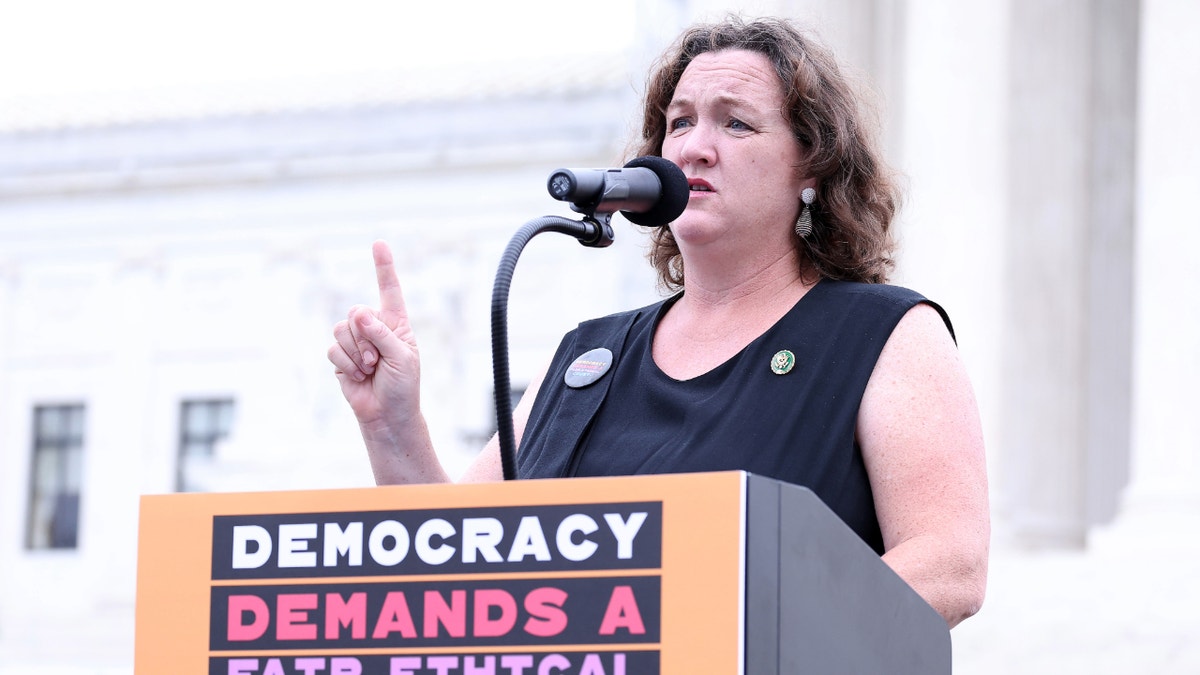 Katie Porter stands at a lectern speaking during a press conference outside the U.S. Capitol.